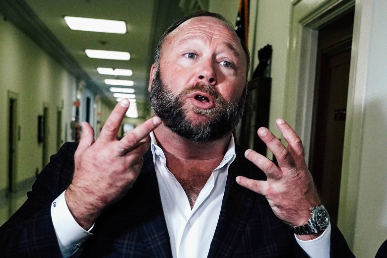 Alex Jones speaking and gesticulating in a hallway.